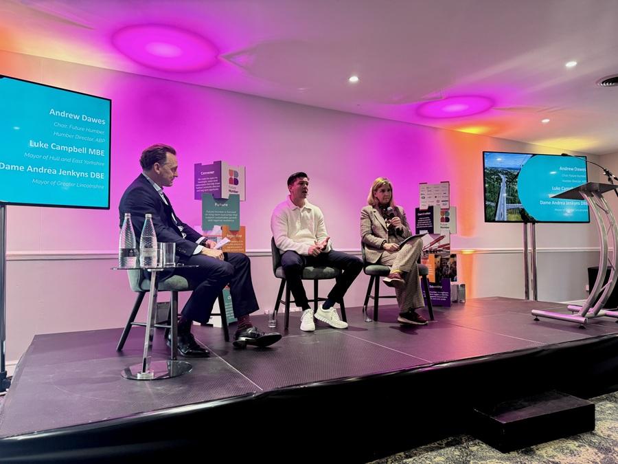 Speakers seated on a stage during a panel discussion at a conference event.