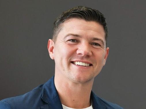 Head-and-shoulders portrait of Mayor Luke smiling against a grey background.