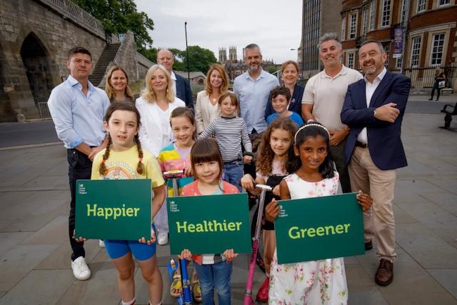 A photograph of Mayor's with children holding placards which say 'Happier', 'Healthier', 'Greener'.
