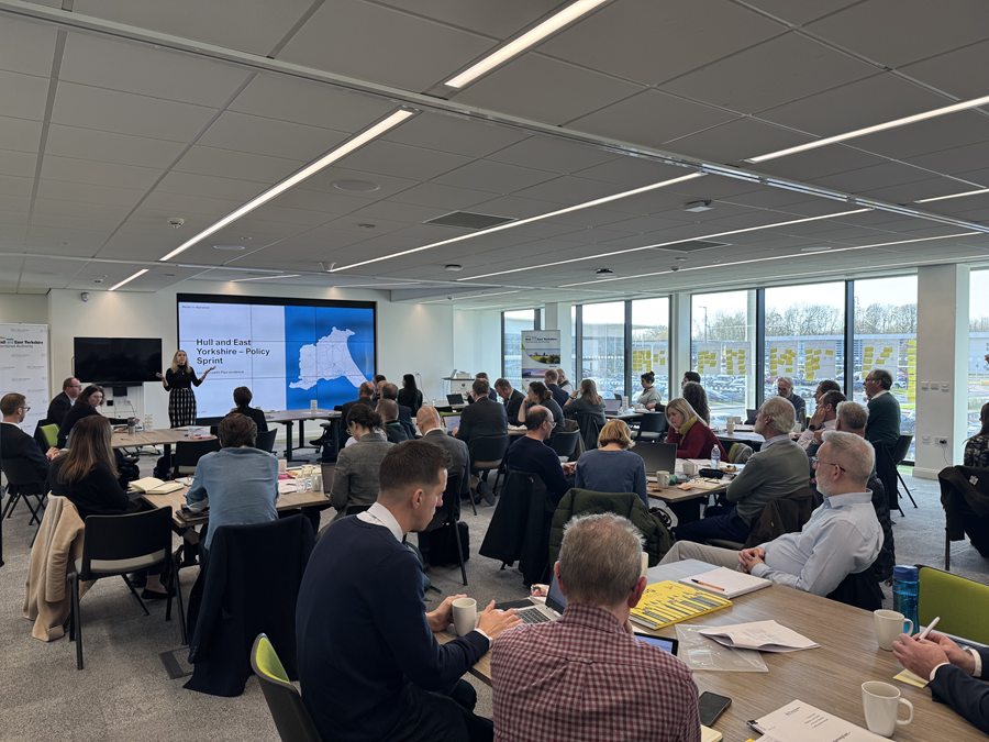 A large group of people seated at tables in a conference room during a policy workshop.