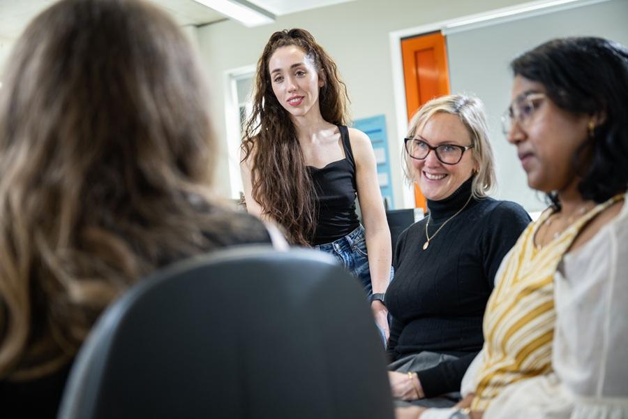 Four women take part in a group discussion during a training session in a bright office.