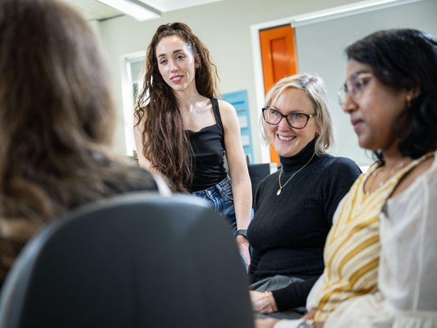 Four women take part in a group discussion during a training session in a bright office.